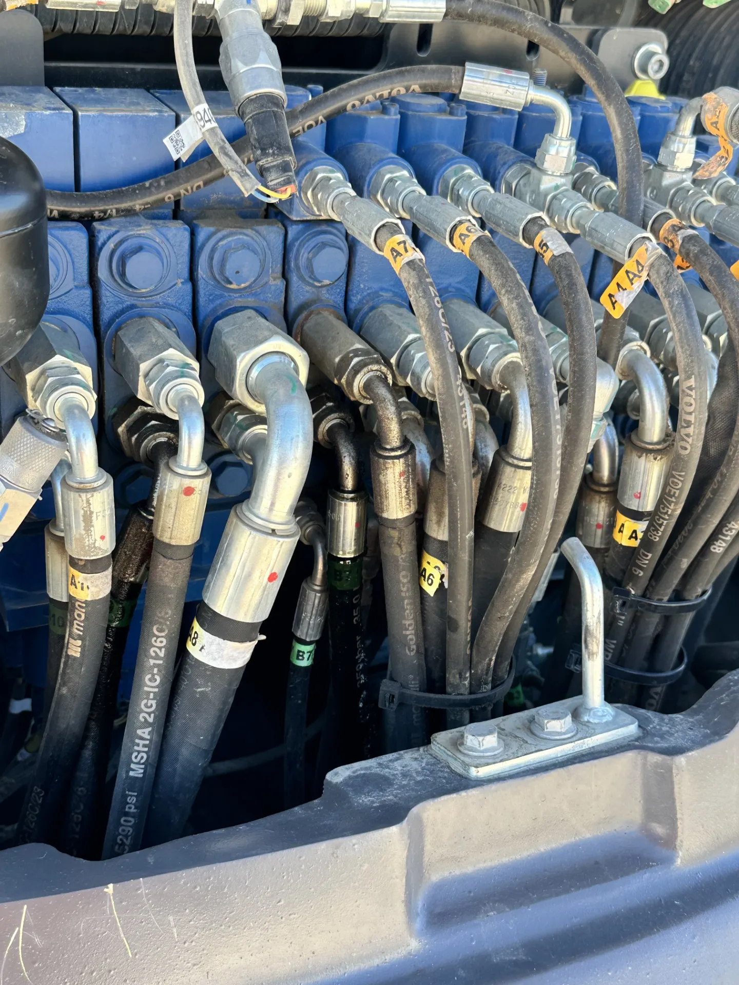 Hydraulic hose bank and fittings on an excavator valve block during hydraulic repairs in Canberra