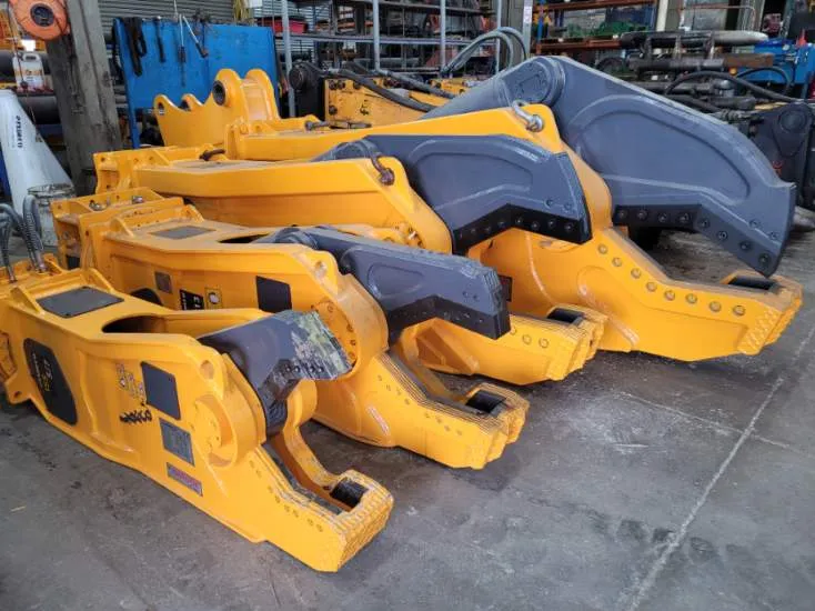 Assorted yellow hydraulic pulveriser and crusher attachments in the workshop for attachment repairs in Canberra