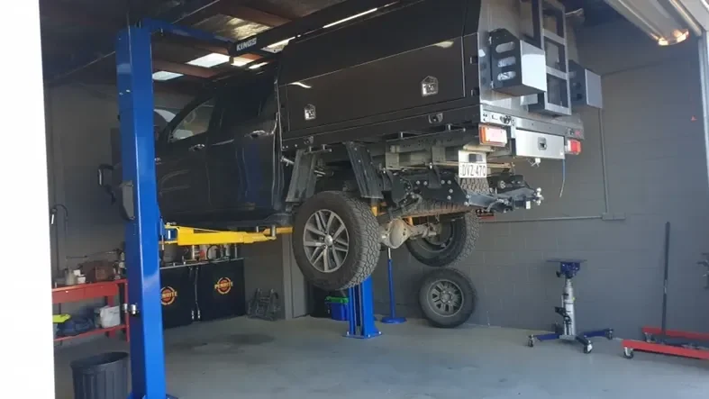 Ute raised on the two-post hoist inside the Queanbeyan hydraulic and mechanical workshop